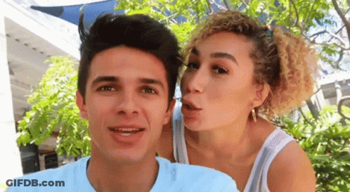 A Woman Is Blowing A Kiss On A Man 'S Face GIF