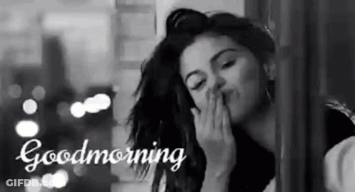 A Woman Is Blowing A Kiss While Looking Out Of A Window . GIF