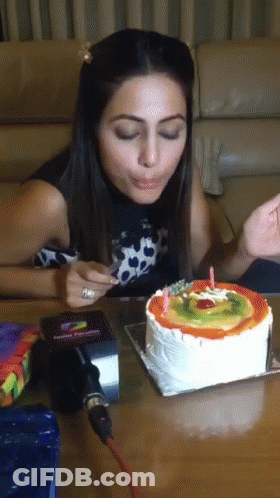 A Woman Is Blowing Out A Candle On A Cake GIF