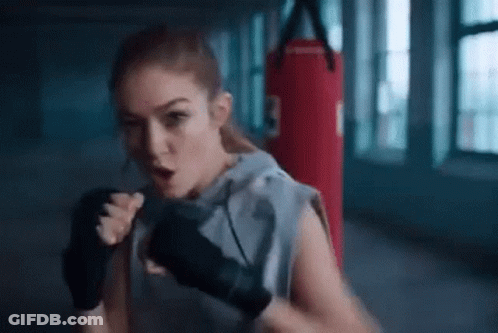 A Woman Is Boxing In A Gym With A Red Punching Bag . GIF