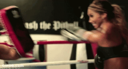 A Woman Is Boxing In A Ring With A Sign Behind Her That Says " Ash The Dust " GIF