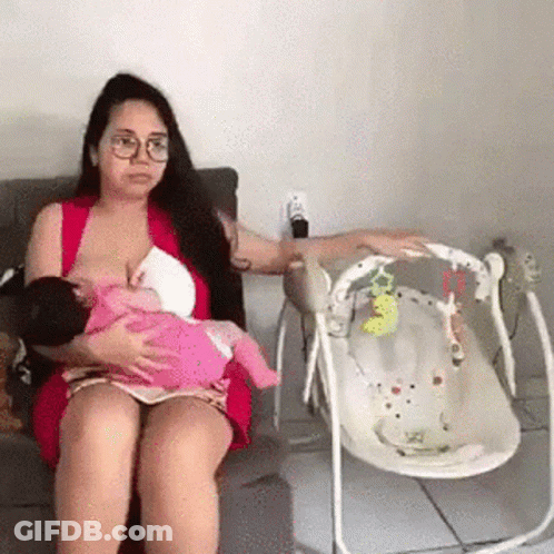 A Woman Is Breastfeeding A Baby While Sitting In A Chair . GIF