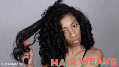 A Woman Is Brushing Her Hair With A Brush And The Words Hair Weave Are Visible Behind Her . GIF