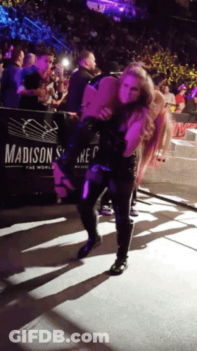 A Woman Is Carrying Another Woman On Her Shoulders In Front Of A Madison Sign GIF