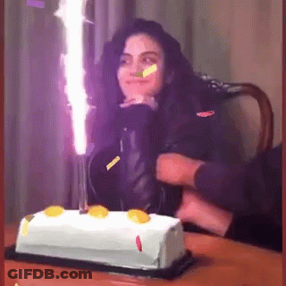 A Woman Is Celebrating Her Birthday With A Cake And Candles GIF