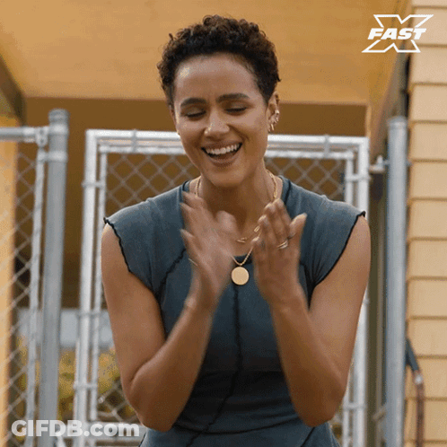 A Woman Is Clapping Her Hands In Front Of A Fence With A X Fast Logo In The Corner GIF