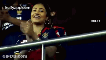 A Woman Is Clapping Her Hands In The Stands During A Cricket Game . GIF
