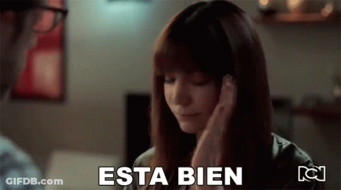 A Woman Is Covering Her Ears With Her Hands And The Word Esta Bien Is Written On The Screen . GIF