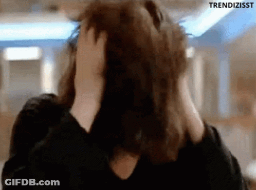 A Woman Is Covering Her Ears With Her Hands While Looking At The Camera . GIF