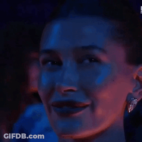 A Woman Is Covering Her Eyes With Her Hand In A Dark Room . GIF