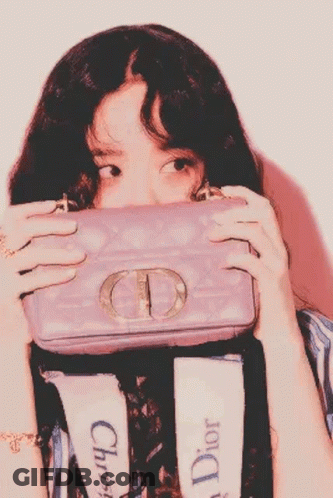 A Woman Is Covering Her Face With A Purple Cd Purse . GIF