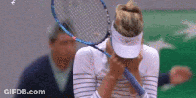 A Woman Is Covering Her Face With A Tennis Racket . GIF