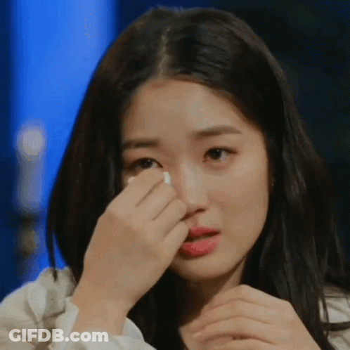 A Woman Is Covering Her Face With Her Hand While Crying GIF
