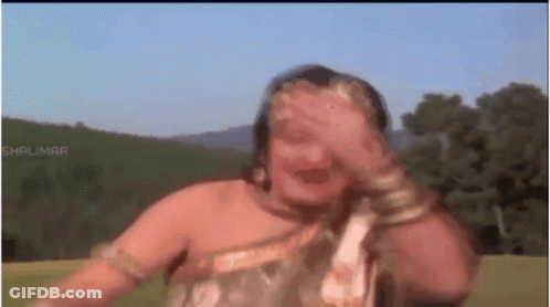 A Woman Is Covering Her Face With Her Hand While Dancing In A Field . GIF