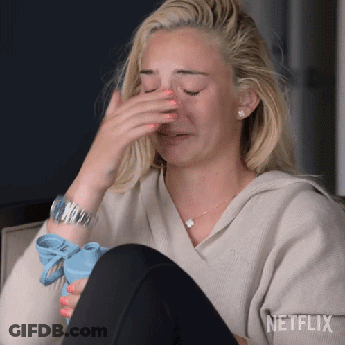A Woman Is Covering Her Face With Her Hand While Holding A Blue Water Bottle .. GIF