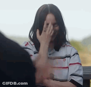 A Woman Is Covering Her Face With Her Hand While Sitting Next To A Man . GIF