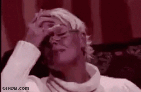A Woman Is Covering Her Face With Her Hand While Sitting On A Couch . GIF