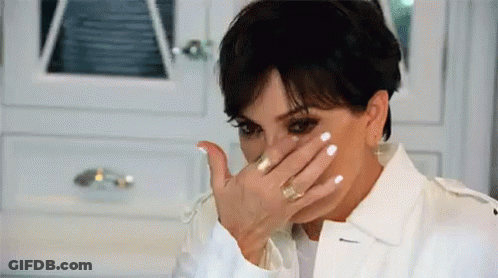 A Woman Is Covering Her Face With Her Hand While Wearing A White Jacket . GIF