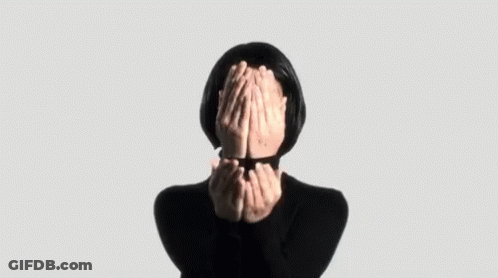 A Woman Is Covering Her Face With Her Hands In A Black Sweater . GIF