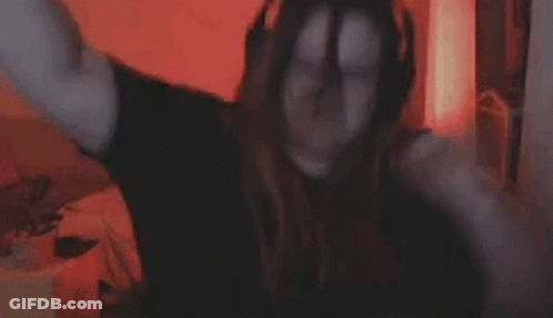 A Woman Is Covering Her Face With Her Hands While Sitting In Front Of A Computer Screen . GIF