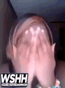 A Woman Is Covering Her Face With Her Hands While Wearing Headphones And A Headband . GIF