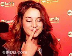 A Woman Is Covering Her Mouth With Her Finger In Front Of A Red Background That Says Family GIF