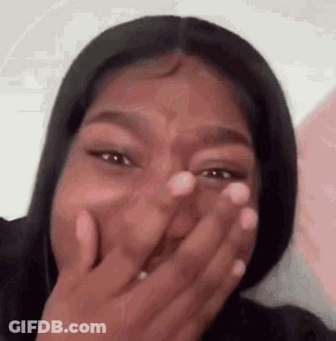 A Woman Is Covering Her Mouth With Her Hand . GIF