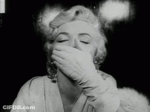 A Woman Is Covering Her Mouth With Her Hand In A Black And White Photo GIF