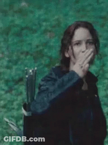 A Woman Is Covering Her Mouth With Her Hand In A Field . GIF