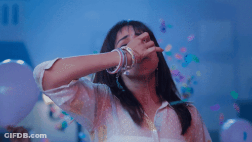A Woman Is Covering Her Mouth With Her Hand While Confetti Falls Around Her GIF