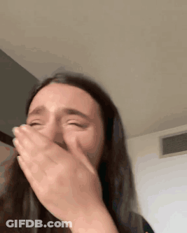 A Woman Is Covering Her Mouth With Her Hands While Crying . GIF