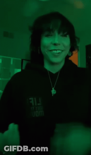 A Woman Is Covering Her Mouth With Her Hands While Wearing A Necklace . GIF