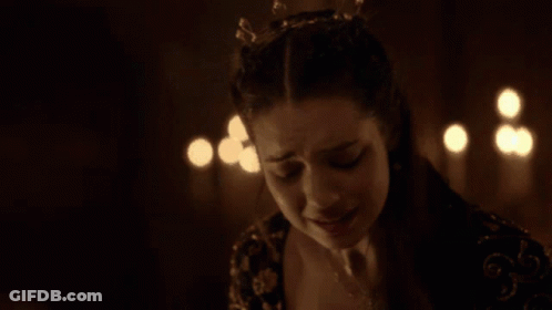 A Woman Is Crying In A Dark Room With Candles Behind Her GIF