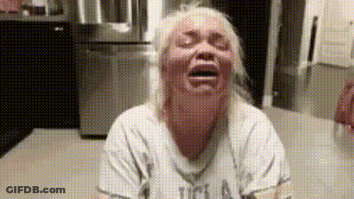A Woman Is Crying In A Kitchen With Her Eyes Closed And Her Mouth Open . GIF