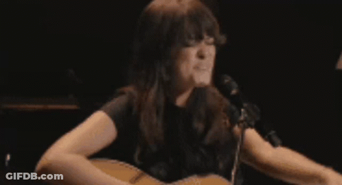 A Woman Is Crying In Front Of A Lamp In A Dark Room GIF