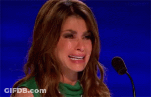 A Woman Is Crying In Front Of A Microphone While Wearing A Green Dress . GIF