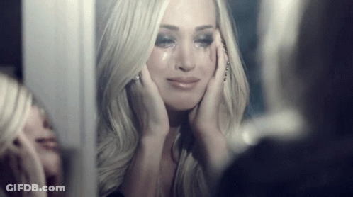 A Woman Is Crying In Front Of A Mirror While Looking At Herself . GIF