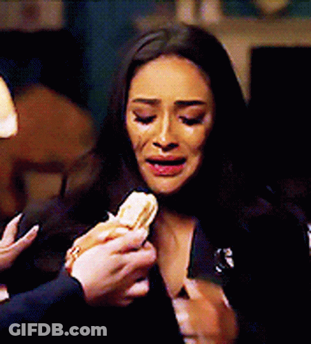 A Woman Is Crying While A Man Is Holding A Sandwich In Front Of Her . GIF