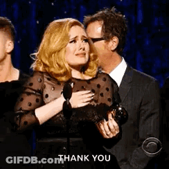 A Woman Is Crying While Holding A Microphone And A Man Is Kissing Her On The Forehead . GIF