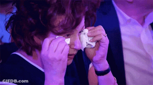 A Woman Is Crying While Holding A Tissue To Her Eye . GIF