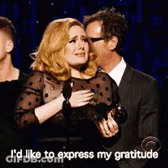 A Woman Is Crying While Holding A Trophy And A Man Is Kissing Her On The Cheek .. GIF