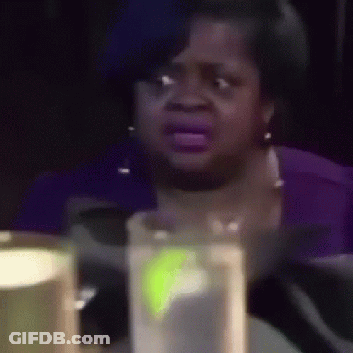 A Woman Is Crying While Sitting At A Table With A Glass Of Water In Front Of Her . GIF