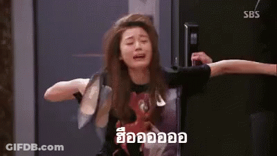 A Woman Is Crying While Sitting On A Chair In Front Of A Door . GIF