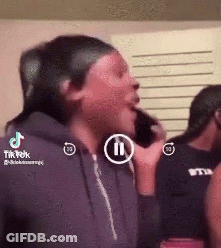 A Woman Is Crying While Talking On A Cell Phone In A Room With Other People . GIF
