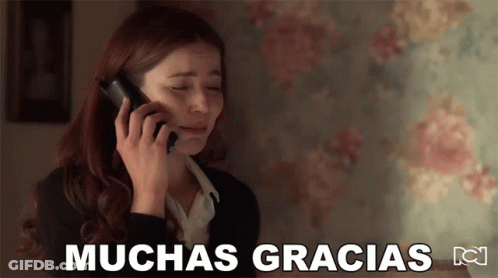 A Woman Is Crying While Talking On A Cell Phone With The Words Muchas Gracias Written Below Her GIF