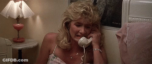 A Woman Is Crying While Talking On A Phone In A Bedroom . GIF