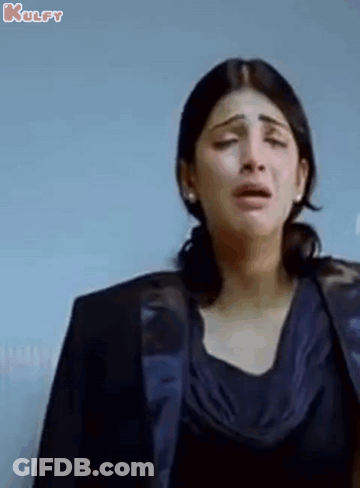 A Woman Is Crying While Wearing A Black Jacket And A Blue Top . GIF