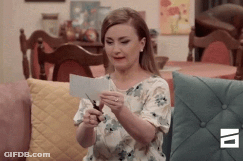 A Woman Is Cutting A Piece Of Paper With Scissors . GIF