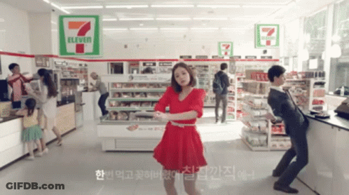 A Woman Is Dancing In A 7 Eleven Store GIF