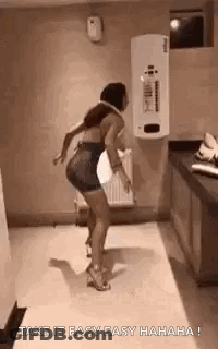A Woman Is Dancing In A Bathroom With The Words `` Take It Easy Easy Hahaha '' Written On The Bottom . GIF